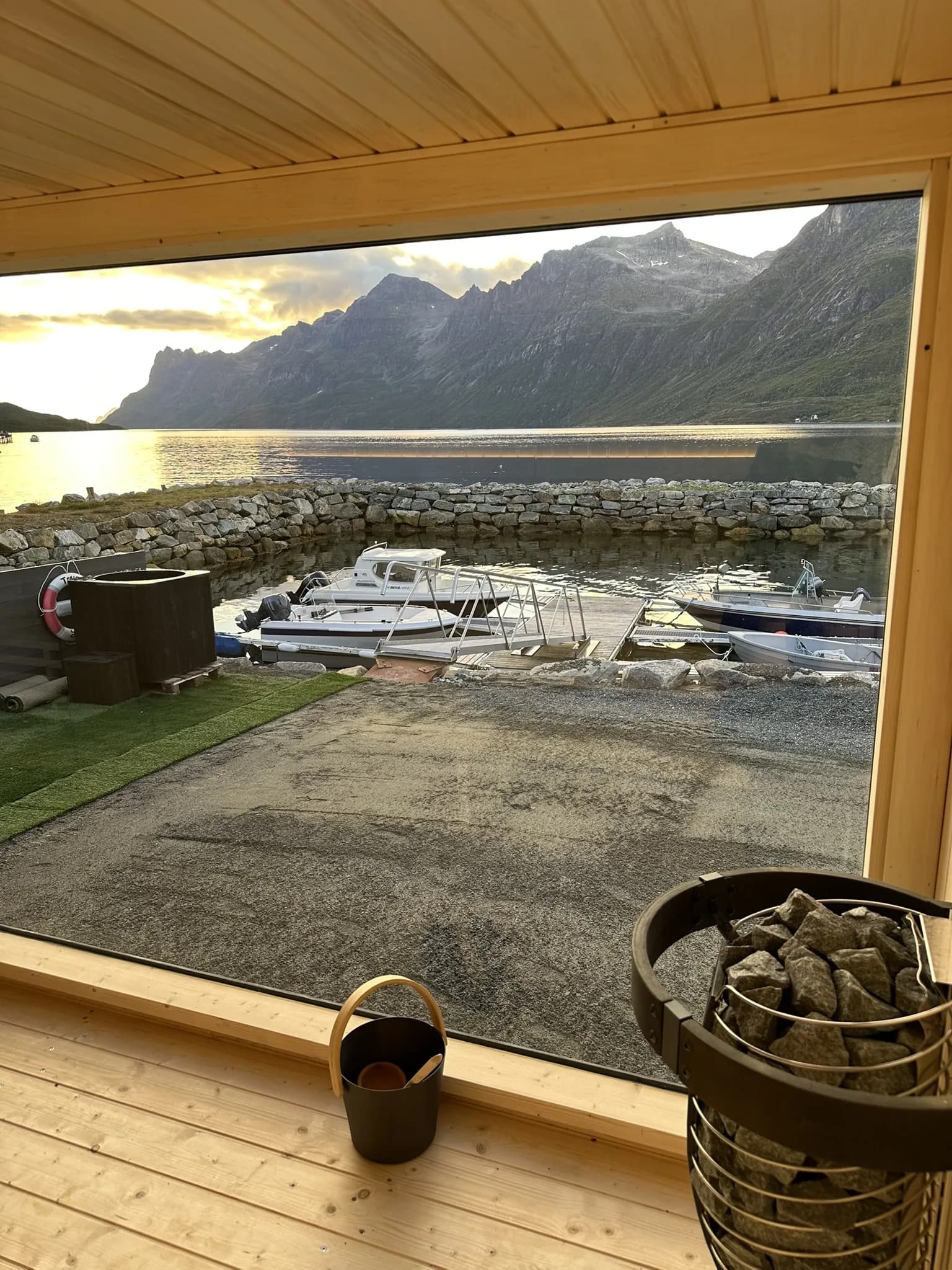 Utsikt fra badstuen gjennom store vinduer mot fjord og snødekte fjell i Ersfjordbotn